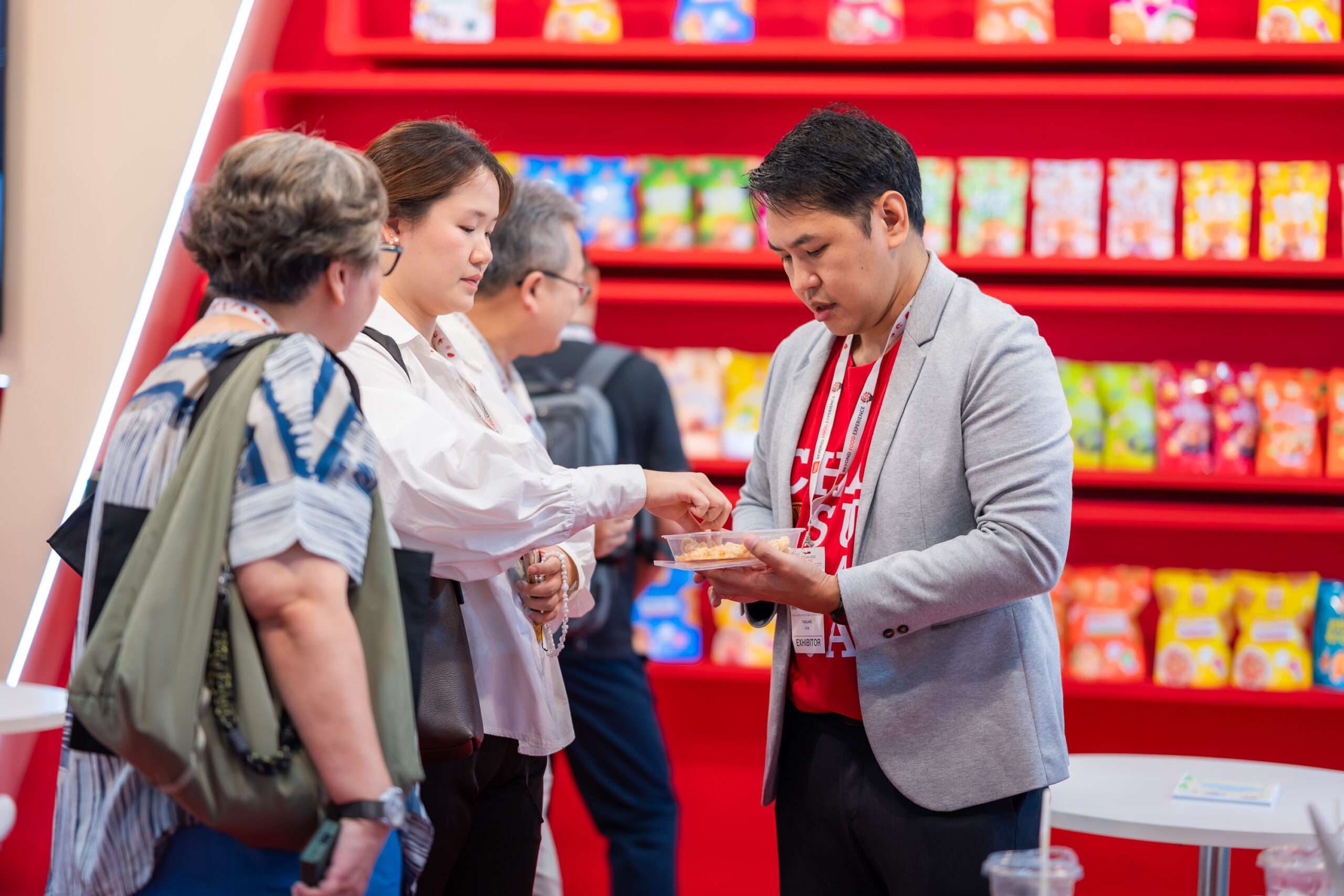 ผู้เข้าร่วมงาน THAIFEX - ANUGA ASIA 2026 กำลังทดลองชิมสินค้าขนมขบเคี้ยวที่บูธของแบรนด์เจ้าสัว