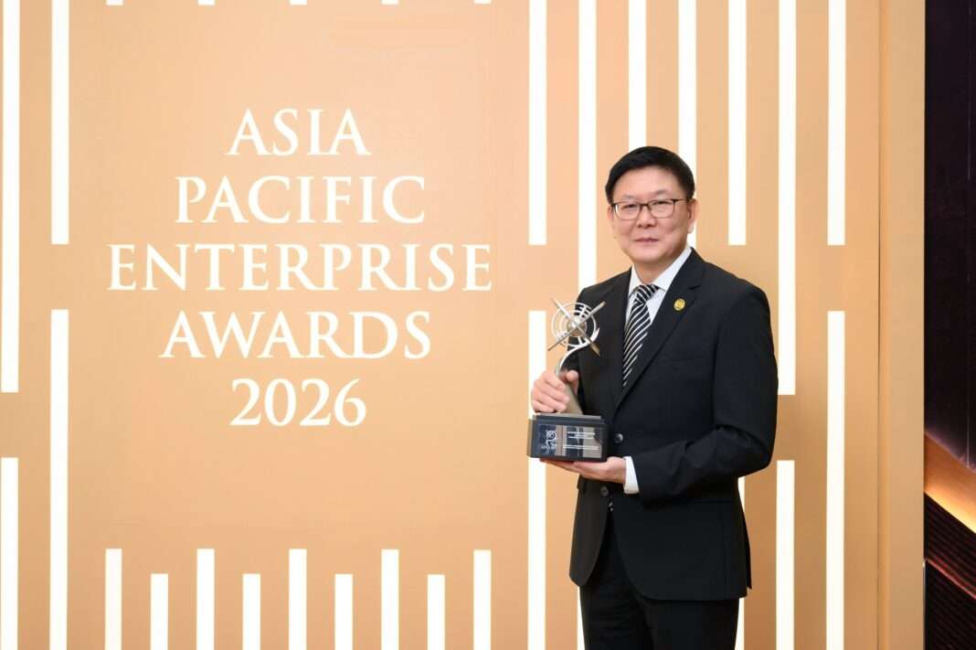 Arkitektura-CEO-Somchai-Master-Entrepreneur-Award-APEA-2026 นายสมชัย อัครวิทยาภูมิ กรรมการผู้จัดการ บริษัท อาร์คิเทคทูรา จำกัด (มหาชน) ถ่ายภาพพอร์ตเทรตพร้อมถือถ้วยรางวัล Master Entrepreneur Award บริเวณหน้าป้ายประกาศรางวัล APEA 2026