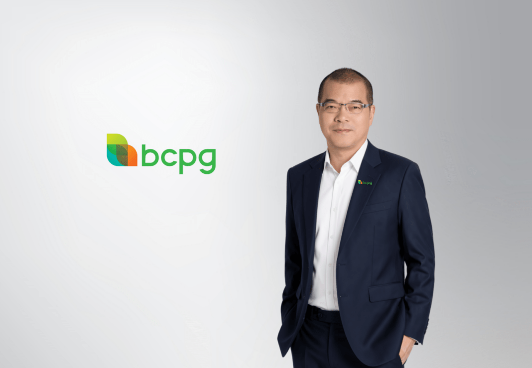 ภาพผู้บริหารระดับสูงของบริษัท บีซีพีจี จำกัด (มหาชน) หรือ BCPG สวมเสื้อเชิ้ตสีขาวทับด้วยสูทสีน้ำเงิน ยืนถ่ายภาพด้วยความมั่นใจคู่กับโลโก้แบรนด์ BCPG เพื่อเตรียมประกาศการจ่ายเงินปันผลระหว่างกาล