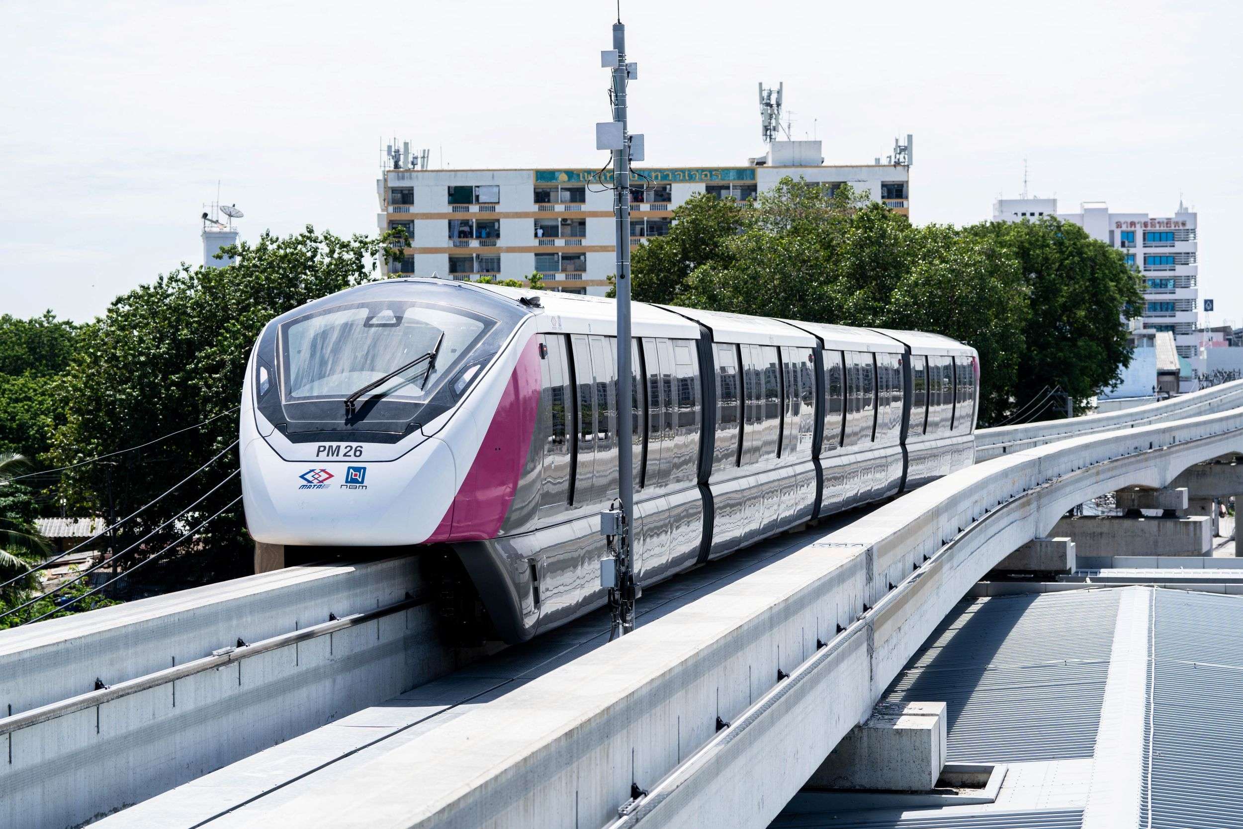 ภาพขบวนรถไฟฟ้าโมโนเรลสายสีชมพูของบีทีเอสกำลังวิ่งให้บริการผู้โดยสารบนรางยกระดับ ท่ามกลางทัศนียภาพของอาคารบ้านเรือนและตึกสูงในกรุงเทพมหานคร