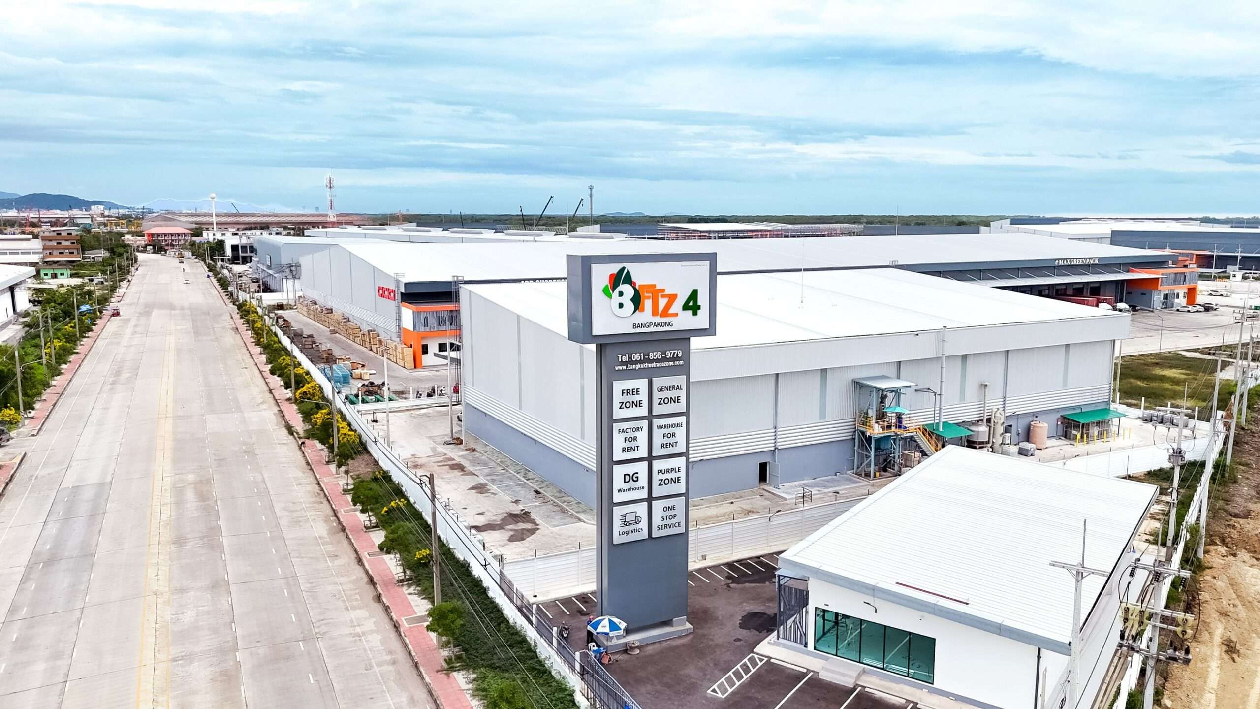 ภาพมุมสูงแสดงป้ายโครงการ BFTZ 4 บางปะกง ด้านหน้าอาคารคลังสินค้าและโรงงานสำเร็จรูปขนาดใหญ่ โซนเขตปลอดอากรและเขตทั่วไป