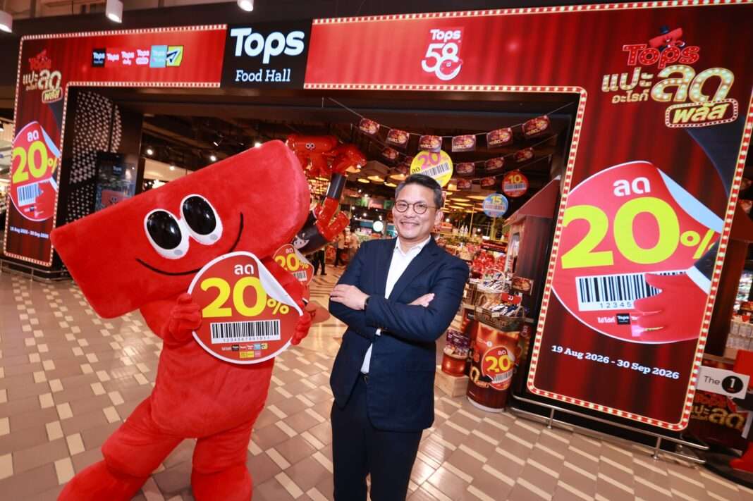 Chakkit-Chatupanyachotikul-Tops-Sticker-Campaign-2026 ภาพนายจักรกฤษณ์ จตุปัญญาโชติกุล รองกรรมการผู้จัดการฝ่ายการตลาดฯ ท็อปส์ ถ่ายภาพคู่กับมาสคอตสติ๊กเกอร์สีแดงและป้ายโปรโมชัน แปะอะไรก็ลด พลัส ลด 20% บริเวณหน้าสาขา Tops Food Hall