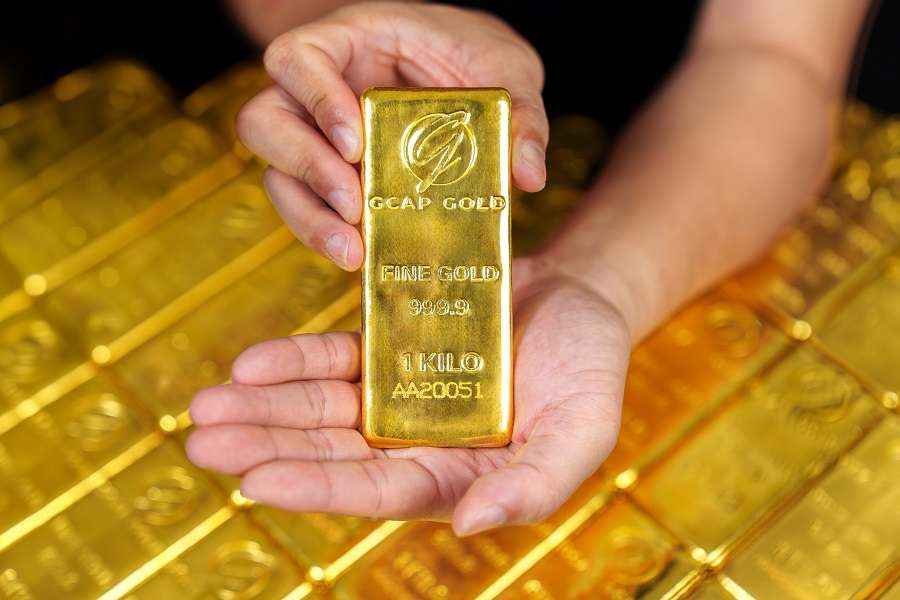 ภาพมือประคองทองคำแท่งความบริสุทธิ์ 999.9 น้ำหนัก 1 กิโลกรัม สลักโลโก้ GCAP GOLD ไว้อย่างชัดเจน โดยมีฉากหลังเป็นทองคำแท่งจำนวนมากวางเรียงรายกัน