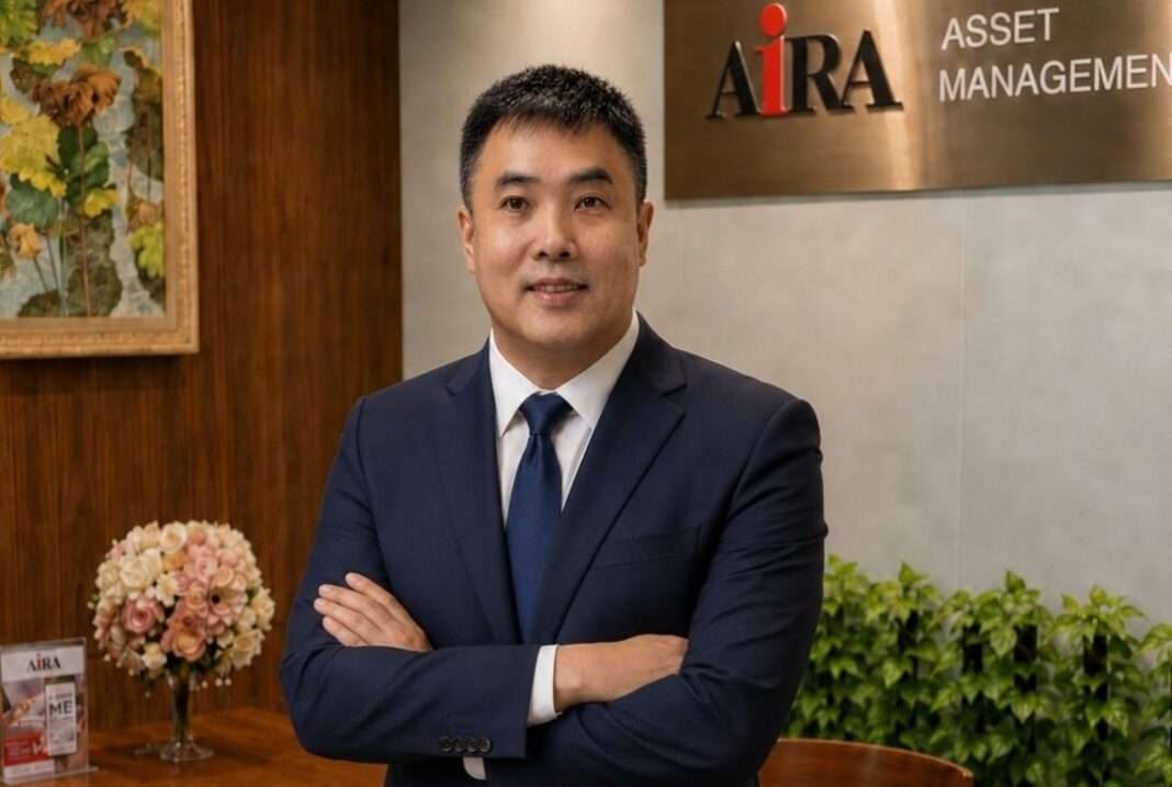 Mok-Swee-Meng-MD-AIRA-Asset-Management-AIAM ภาพนายมอค สวี เม้ง กรรมการผู้จัดการ บริษัทหลักทรัพย์จัดการกองทุน ไอร่า จำกัด (AIAM) สวมชุดสูทสากลสีน้ำเงินผูกเนกไท ยืนกอดอกถ่ายภาพด้วยความมั่นใจ โดยมีฉากหลังเป็นป้ายโลโก้ AIRA ASSET MANAGEMENT