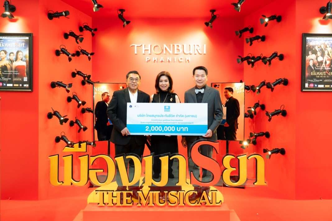 ภาพคุณนุสรา (อัสสกุล) บัญญัติปิยพจน์ ประธานเจ้าหน้าที่บริหารและกรรมการผู้จัดการ บริษัท ไทยสมุทรประกันชีวิต จำกัด (มหาชน) ร่วมถ่ายภาพขณะส่งมอบป้ายเงินสนับสนุนจำนวน 2,000,000 บาท แก่ศาสตราจารย์ นายแพทย์ปิยะมิตร ศรีธรา ประธานคณะกรรมการมูลนิธิมหาวิทยาลัยมหิดลฯ ท่ามกลางฉากหลังสีแดงของงานละครเวทีรอบการกุศล เมืองมารยา เดอะมิวสิคัล