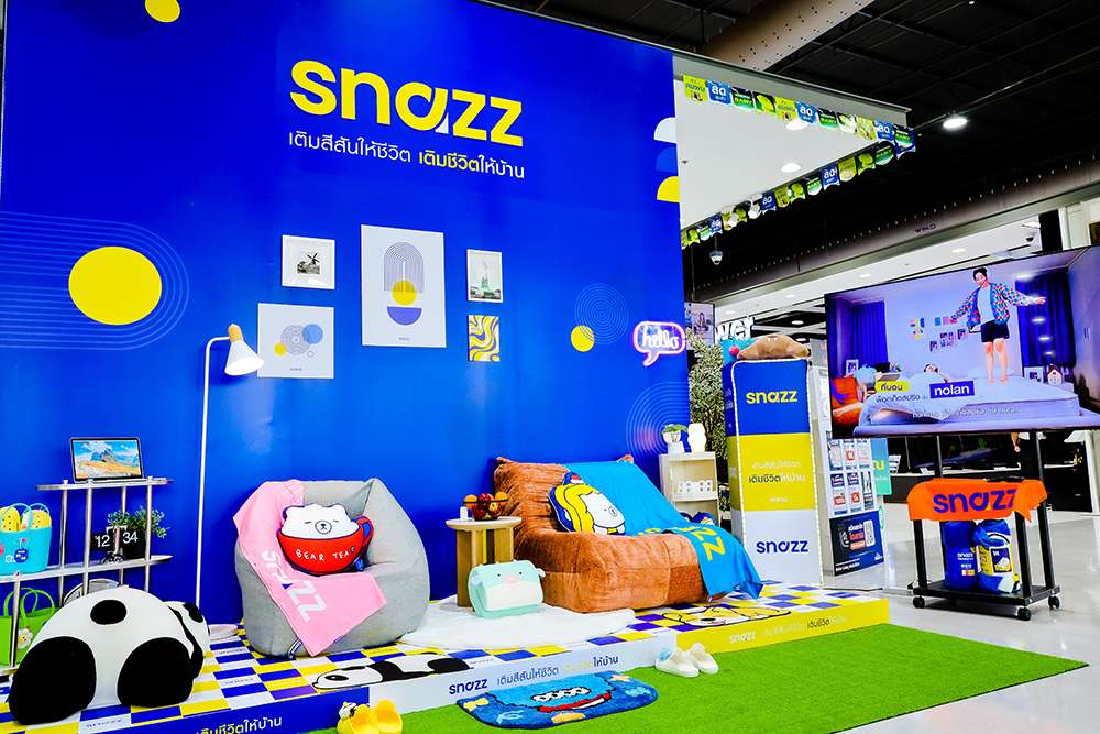 พื้นที่จัดแสดงสินค้าแบรนด์ SNAZZ ภายในโฮมโปร โดดเด่นด้วยโทนสีน้ำเงินและเหลือง ประกอบด้วยเฟอร์นิเจอร์ชิ้นเล็ก เบาะนั่ง พรม และของตกแต่งบ้านสีสันสดใส