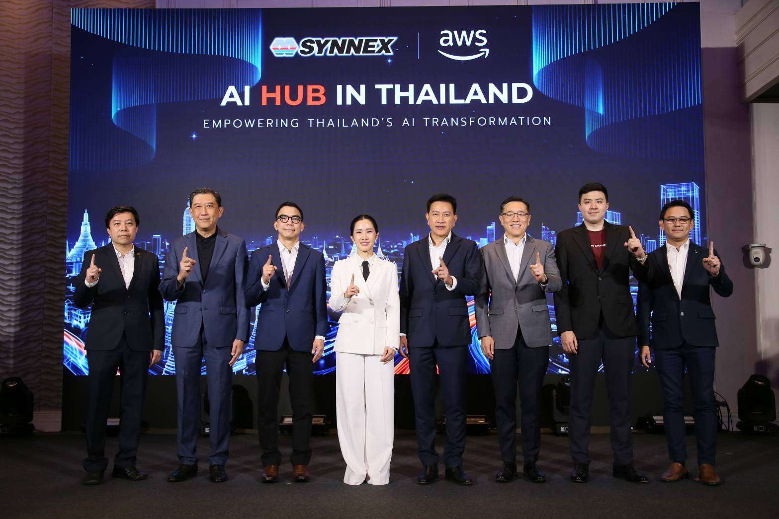 ภาพคุณสุธิดา มงคลสุธี ประธานเจ้าหน้าที่บริหาร บริษัท ซินเน็ค (ประเทศไทย) จำกัด (มหาชน) สวมชุดสูทสีขาว ยืนถ่ายภาพร่วมกับคณะผู้บริหารจาก SYNNEX พันธมิตร AWS และองค์กรชั้นนำ บนเวทีงานเปิดตัว AI HUB IN THAILAND