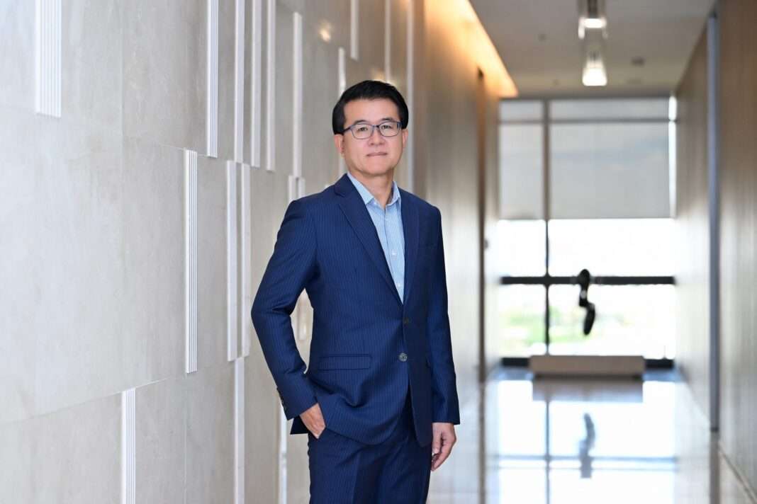 Chongrak-Rattanapian-KBank-Subordinated-Bond-800M-USD ภาพนายจงรัก รัตนเพียร ผู้จัดการใหญ่ ธนาคารกสิกรไทย สวมชุดสูทสีน้ำเงิน ยืนล้วงกระเป๋าถ่ายภาพด้วยความมั่นใจบริเวณโถงทางเดิน เพื่อประกาศความสำเร็จในการออกหุ้นกู้ด้อยสิทธิมูลค่า 800 ล้านดอลลาร์สหรัฐ