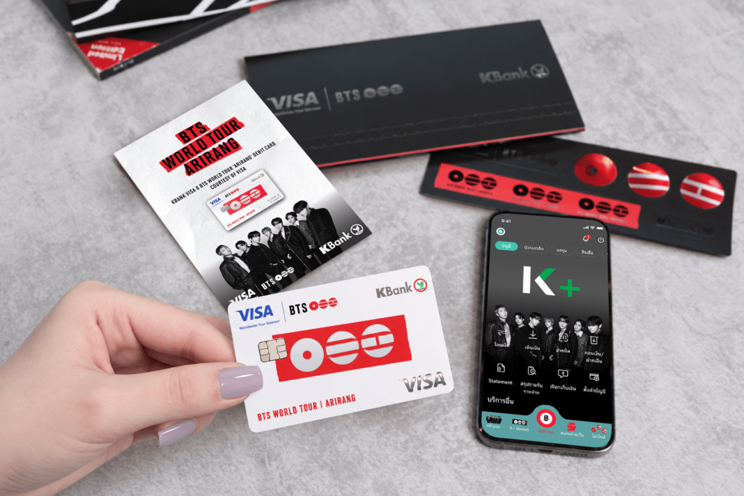 ภาพมือถือบัตรเดบิต KBANK VISA & BTS WORLD TOUR ‘ARIRANG’ ดีไซน์สีขาวตัดกับโลโก้สีแดง โดดเด่นเคียงคู่กับสมาร์ตโฟนที่แสดงหน้าจอแอปพลิเคชัน K PLUS ในธีม BTS พร้อมโปสการ์ดรูปศิลปินทั้ง 7 คน และชุดสติกเกอร์ครบเซ็ต