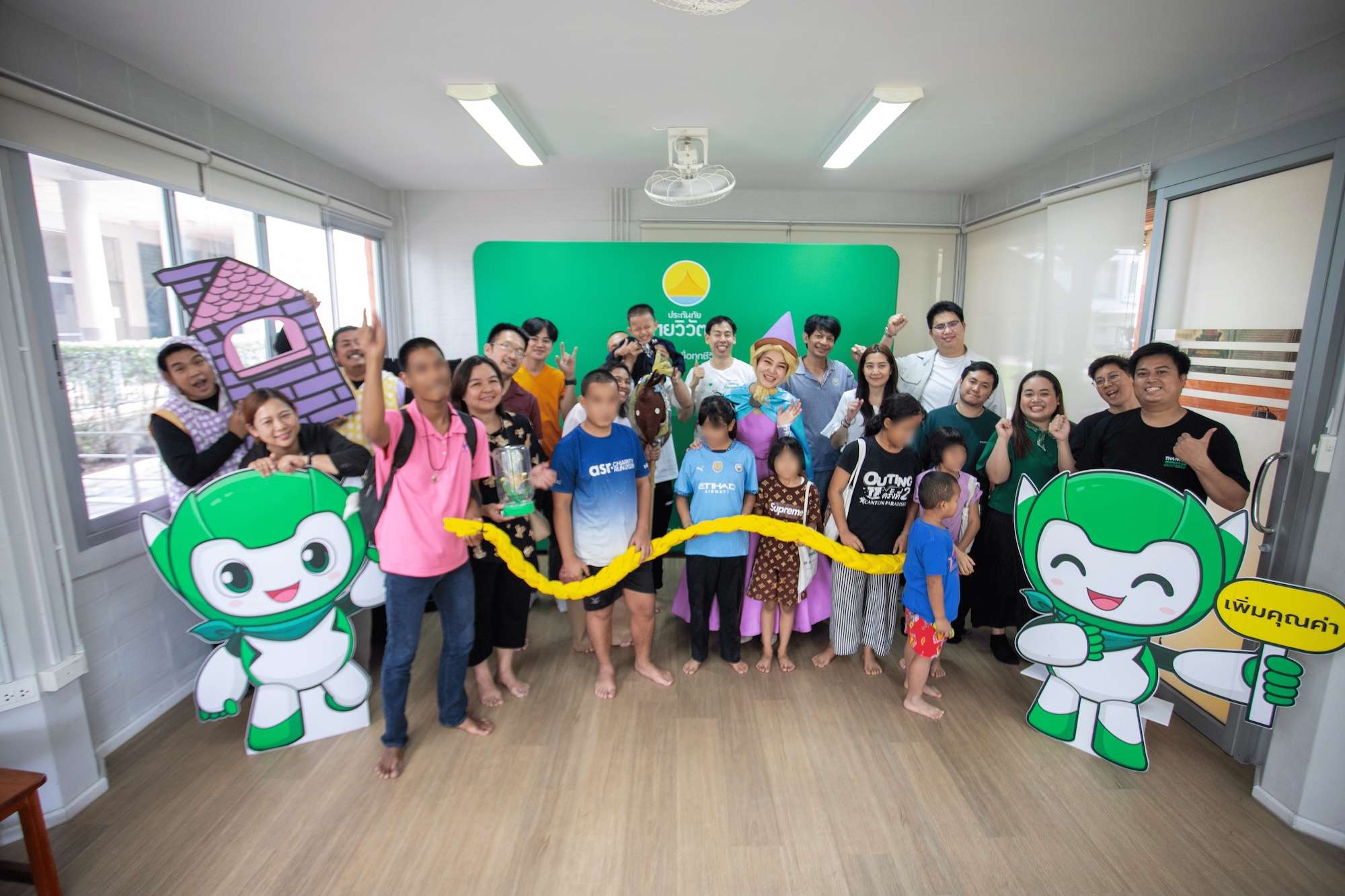 ภาพกลุ่มพนักงานประกันภัยไทยวิวัฒน์ถ่ายภาพร่วมกับเด็กๆ และผู้ร่วมกิจกรรมอย่างอบอุ่นและสนุกสนาน พร้อมด้วยป้ายสแตนดี้มาสคอตน้องไทวี่ในโครงการ Thaivivat Caring Forward