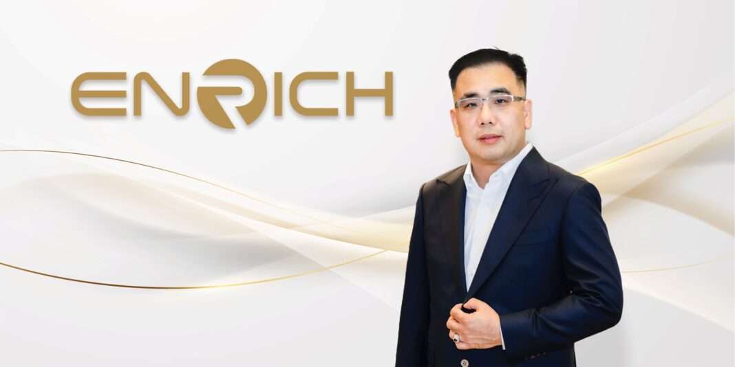 Akarawat-Chandaensuwan-CEO-ENRICH-IPO-Filing-mai นายอัครวัฒน์ ฉันทแดนสุวรรณ ประธานเจ้าหน้าที่บริหาร บริษัท ริชเชส ซัพพลาย จำกัด (มหาชน) หรือ ENRICH สวมชุดสูทสีกรมท่ายืนถ่ายภาพด้วยความมั่นใจ ด้านหลังมีโลโก้ ENRICH สีทองบนพื้นหลังสีขาว