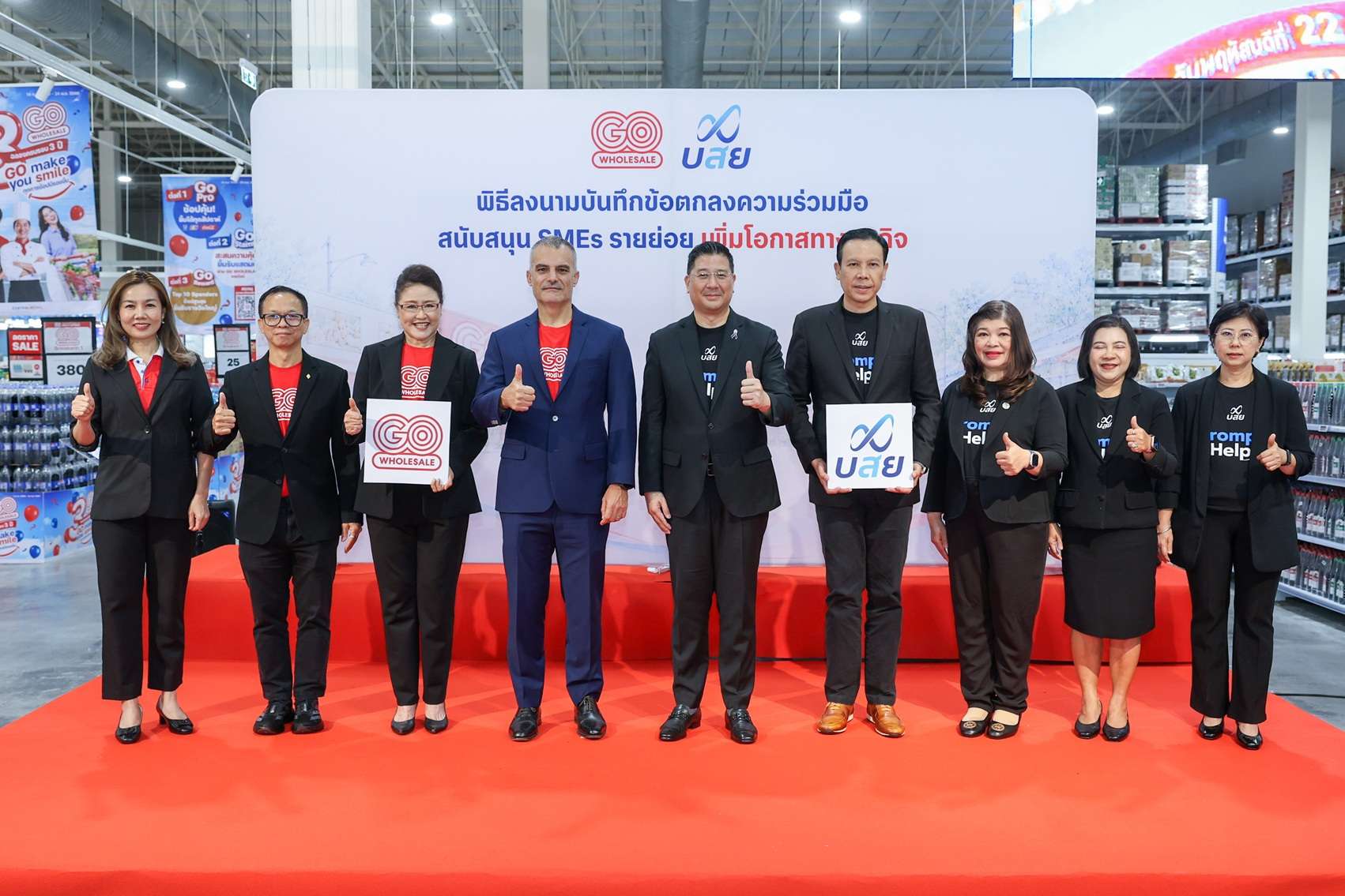ผู้บริหารจากโก โฮลเซลล์ และบรรษัทประกันสินเชื่ออุตสาหกรรมขนาดย่อม (บสย.) ถ่ายภาพหมู่ร่วมกันบนเวที หลังเสร็จสิ้นพิธีลงนามบันทึกข้อตกลงความร่วมมือ
