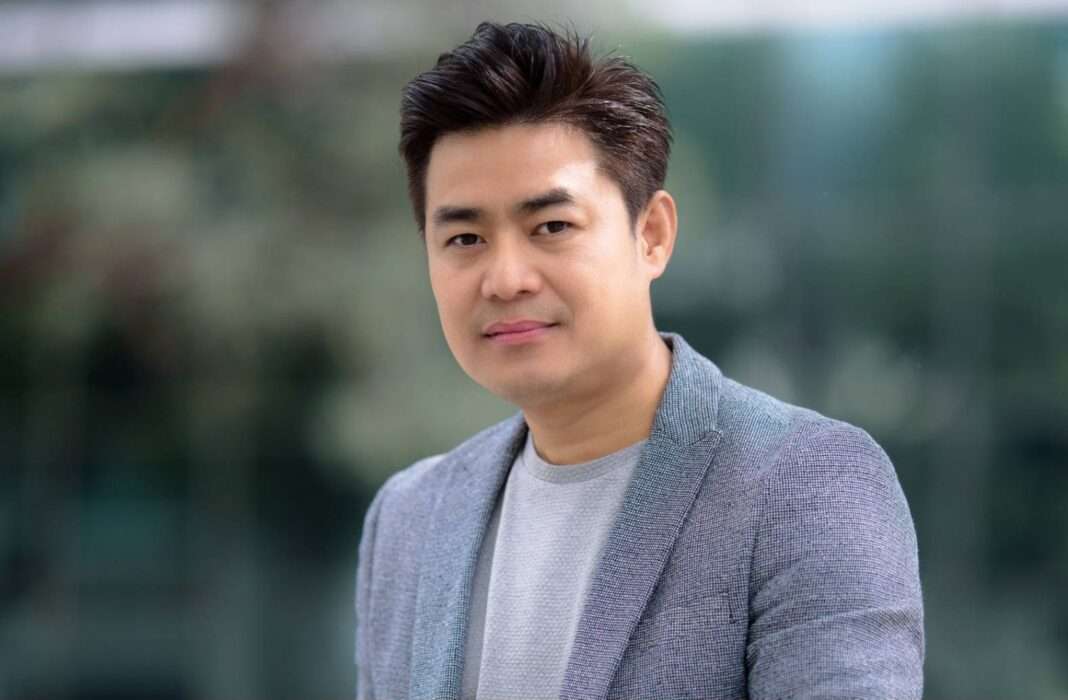 นายกิตติพันธ์ ศรีบัวเอี่ยม ประธานเจ้าหน้าที่บริหาร บริษัท โปรเอ็น คอร์ป จำกัด (มหาชน) หรือ PROEN สวมเสื้อยืดสีเทาทับด้วยเสื้อสูทสากลสีเทา ถ่ายภาพครึ่งตัวด้วยสีหน้ายิ้มแย้มและมั่นใจ