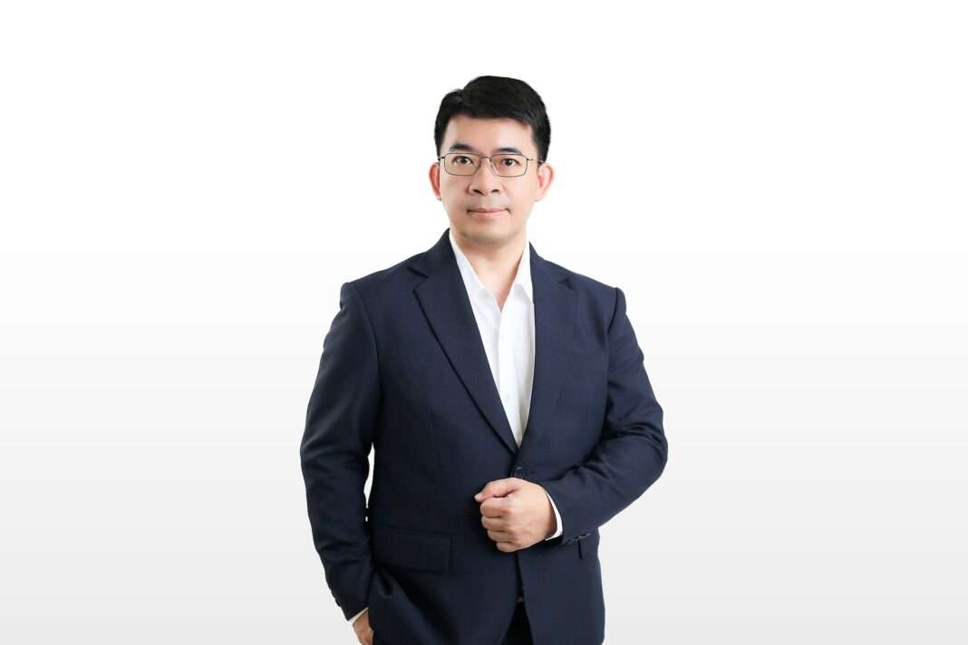 นายไพศาล แซ่ลี้ ประธานเจ้าหน้าที่บริหาร บริษัท ควิก ทรานส์ฟอร์เมชั่น จำกัด (มหาชน) หรือ QUICK สวมชุดสูทสากลสีน้ำเงินทับเสื้อเชิ้ตสีขาว ยืนถ่ายภาพด้วยความมั่นใจบนพื้นหลังสีขาวล้วน