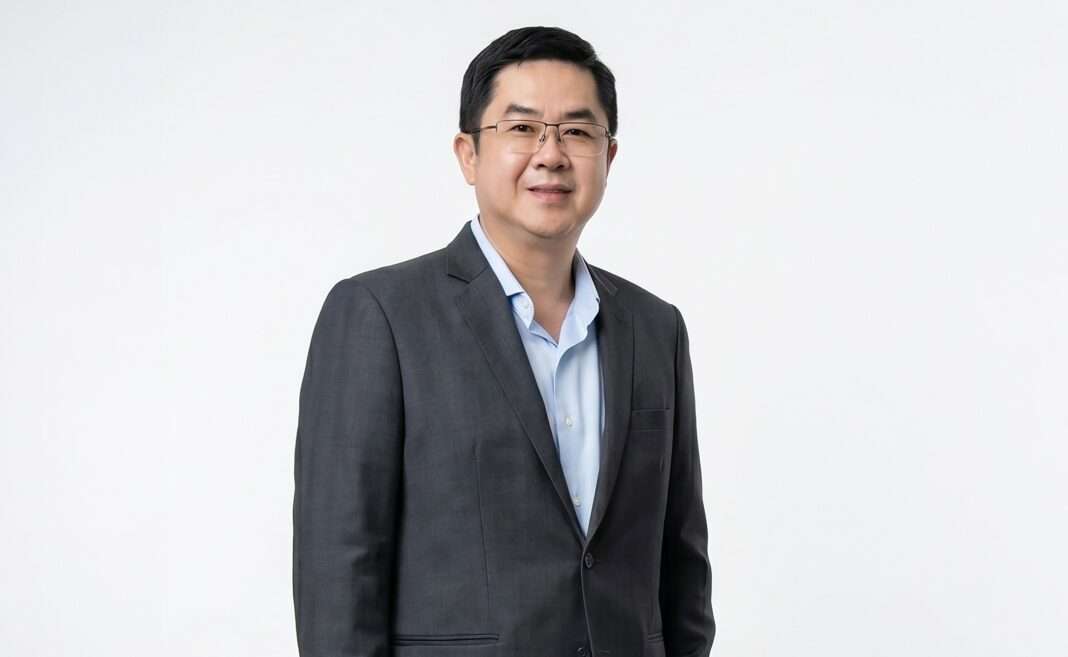 Pornsak-Tantapakul-CEO-Dental-Corporation-Public-Company-Limited นายพรศักดิ์ ตันตาปกุล ประธานเจ้าหน้าที่บริหาร บริษัท เดนทัล คอร์ปอเรชั่น จำกัด (มหาชน) หรือ D สวมเสื้อสูทสีเทาทับเสื้อเชิ้ตสีฟ้า ยืนถ่ายภาพด้วยความมั่นใจ