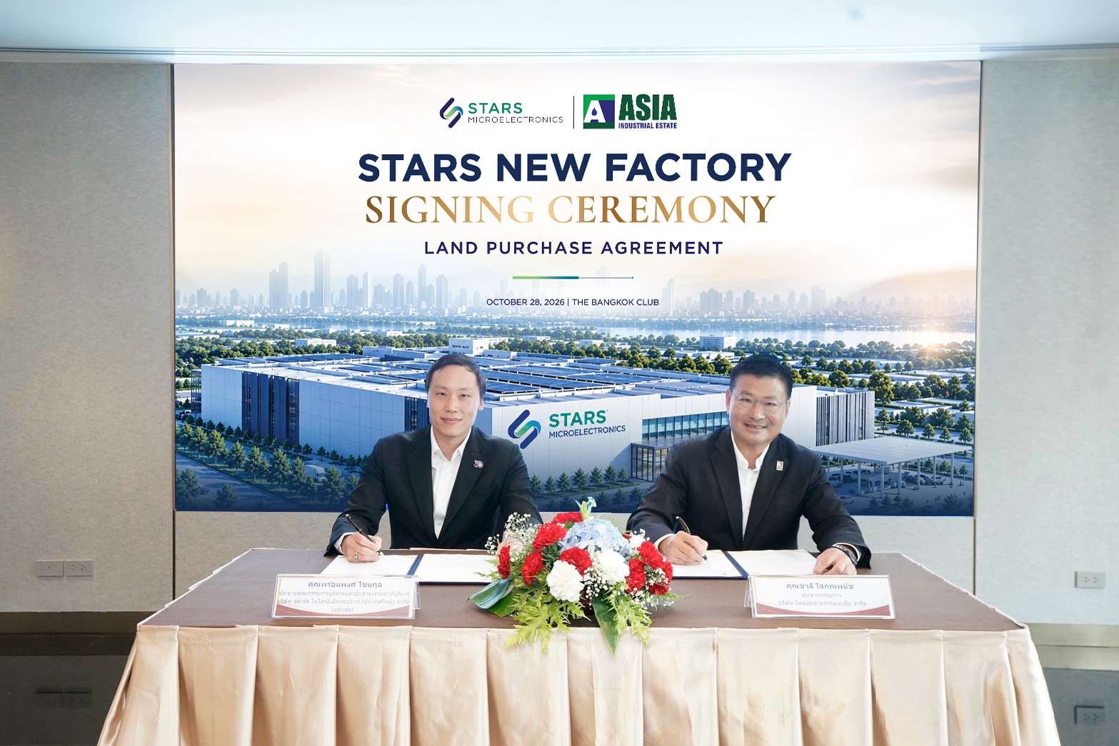 ภาพนายพร้อมพงศ์ ไชยกุล ประธานเจ้าหน้าที่บริหาร SMT (ซ้าย) และนายชาลี โสภณพนิช ประธานกรรมการ AIE (ขวา) กำลังลงนามในสัญญาซื้อขายที่ดินร่วมกัน บนโต๊ะที่ตกแต่งด้วยแจกันดอกไม้ โดยมีฉากหลังเป็นป้ายงาน STARS NEW FACTORY SIGNING CEREMONY พร้อมภาพจำลองโรงงานแห่งใหม่