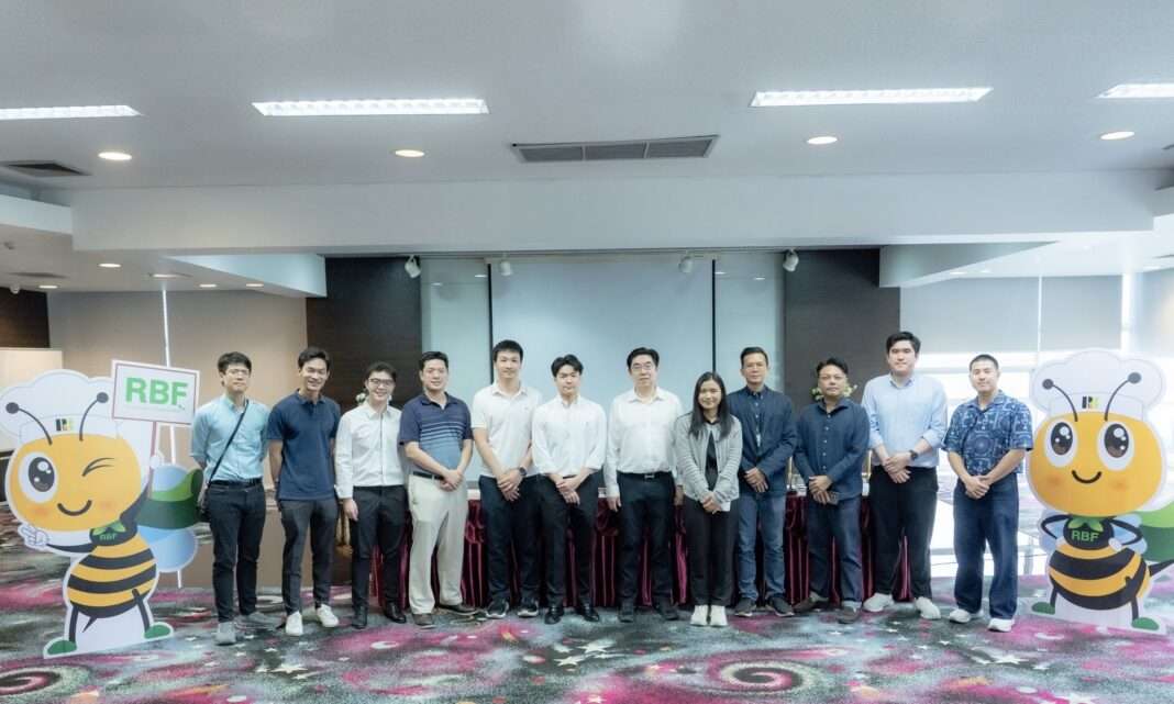 Suranart-Kittirattanadetch-CFO-RBF-Analyst-Meeting-2026 นายสุรนาถ กิตติรัตนเดช ประธานเจ้าหน้าที่ฝ่ายบัญชีและการเงิน บริษัท อาร์ แอนด์ บี ฟู้ด ซัพพลาย จำกัด (มหาชน) หรือ RBF ถ่ายภาพหมู่ร่วมกับคณะนักวิเคราะห์และผู้จัดการกองทุนในงานเยี่ยมชมกิจการ โดยมีสแตนดี้มาสคอตของบริษัทตั้งอยู่ด้านข้าง