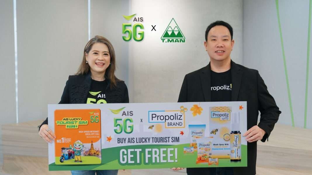 ผู้บริหารหญิงจาก AIS และนายธนัท พลอยดนัย ผู้อำนวยการฝ่ายการตลาดจาก TMAN ยืนถือป้ายโปรโมตแคมเปญส่งเสริมการตลาด AIS 5G ร่วมกับ Propoliz มอบสิทธิพิเศษสำหรับนักท่องเที่ยวต่างชาติเมื่อซื้อ AIS LUCKY TOURIST SIM