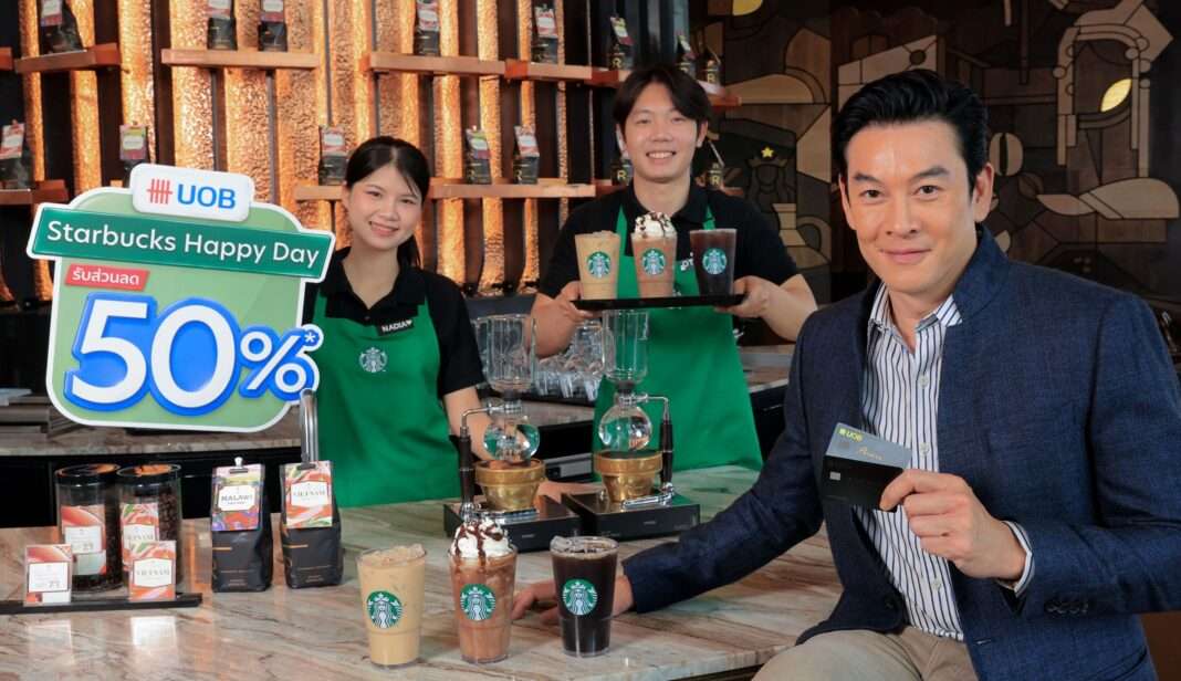 UOB-Starbucks-Happy-Day-Campaign-Chakrit-Yamnam คุณชาคริต แย้มนาม UOB Dining Ambassador สวมชุดสูททับเสื้อเชิ้ตลายทาง ถือบัตรเครดิตยูโอบี ถ่ายภาพร่วมกับพนักงานบาริสต้าและเครื่องดื่มสตาร์บัคส์ พร้อมป้ายแคมเปญ UOB Starbucks Happy Day รับส่วนลด 50% ณ ร้านสตาร์บัคส์