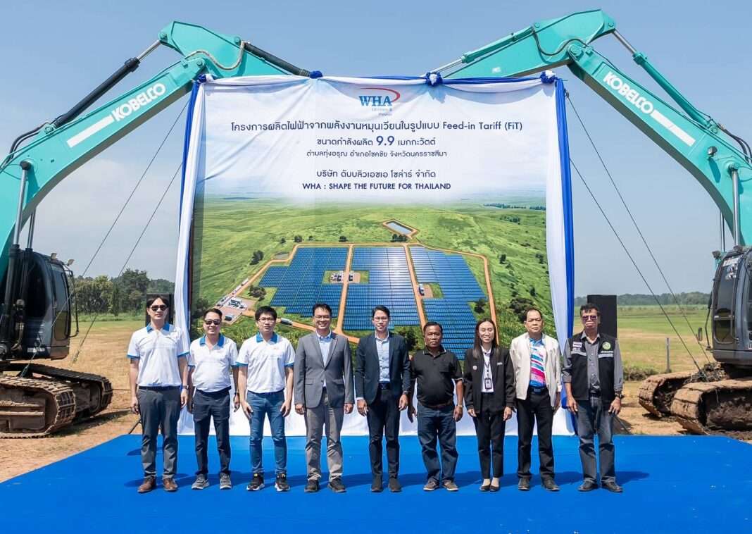 WHAUP-Solar-Farm-FiT-Construction-Nakhon-Ratchasima นายอัครินทร์ ประเทืองสิทธิ์ ประธานเจ้าหน้าที่บริหาร บริษัท ดับบลิวเอชเอ ยูทิลิตี้ส์ แอนด์ พาวเวอร์ จำกัด (มหาชน) หรือ WHAUP พร้อมด้วยคณะผู้บริหาร ตัวแทนองค์กรปกครองส่วนท้องถิ่น และการไฟฟ้าส่วนภูมิภาค ถ่ายภาพร่วมกันในพิธีเริ่มโครงการก่อสร้างโรงไฟฟ้าพลังงานแสงอาทิตย์ (Solar Farm) ขนาด 9.9 เมกะวัตต์ โดยมีฉากหลังเป็นป้ายแสดงภาพโครงการและมีรถแบ็คโฮสีเขียวจอดขนาบข้าง ณ จังหวัดนครราชสีมา