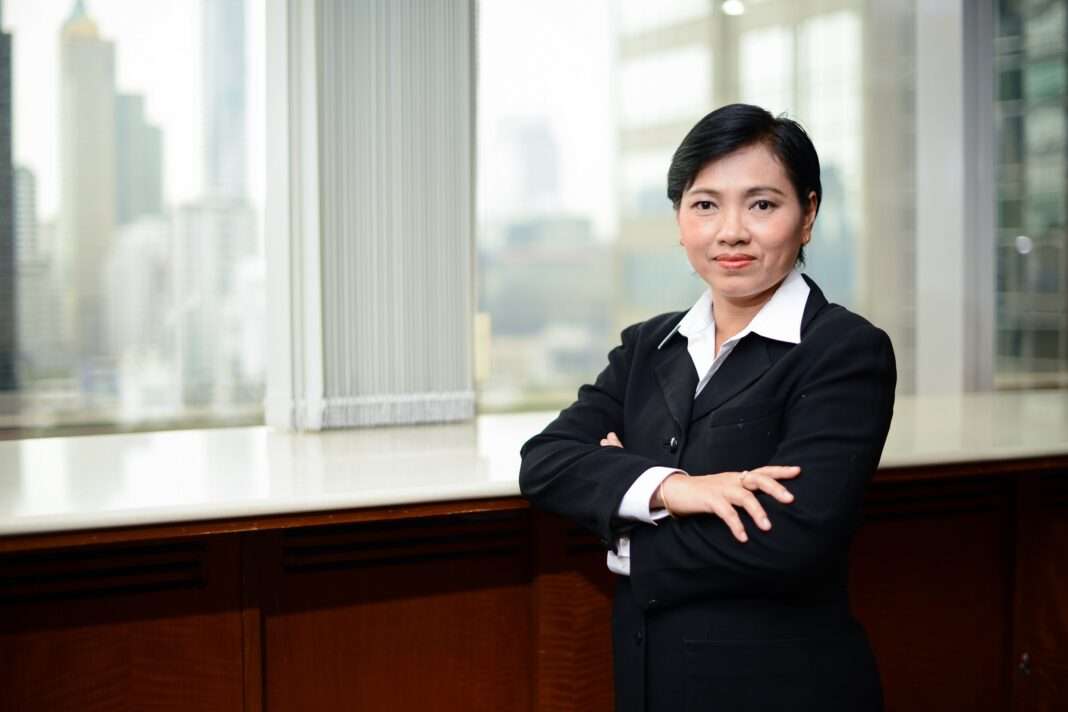 Wilasinee-Boonmasungsong-Globlex-Securities-GBS-Executive ภาพนางสาววิลาสินี บุญมาสูงทรง ผู้ช่วยกรรมการผู้จัดการ บริษัทหลักทรัพย์ โกลเบล็ก จำกัด หรือ GBS สวมชุดสูทสีดำ ยืนกอดอกส่งรอยยิ้มอย่างมั่นใจ โดยมีฉากหลังเป็นหน้าต่างกระจกบานใหญ่ที่มองเห็นวิวตึกระฟ้าในเมือง