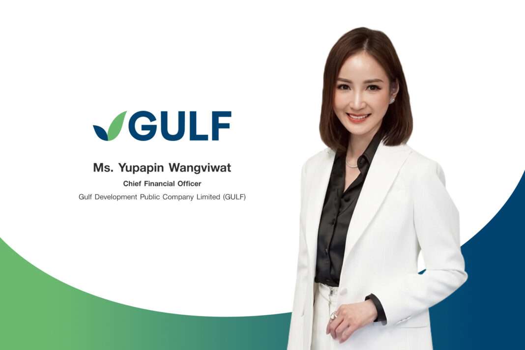 ภาพนางสาวยุพาพิน วังวิวัฒน์ ประธานเจ้าหน้าที่บริหารด้านการเงิน บริษัท กัลฟ์ ดีเวลลอปเมนท์ จำกัด (มหาชน) หรือ GULF สวมชุดสูทสีขาวทับเสื้อเชิ้ตสีดำ ยืนส่งรอยยิ้มด้วยความมั่นใจ เคียงข้างโลโก้แบรนด์ GULF