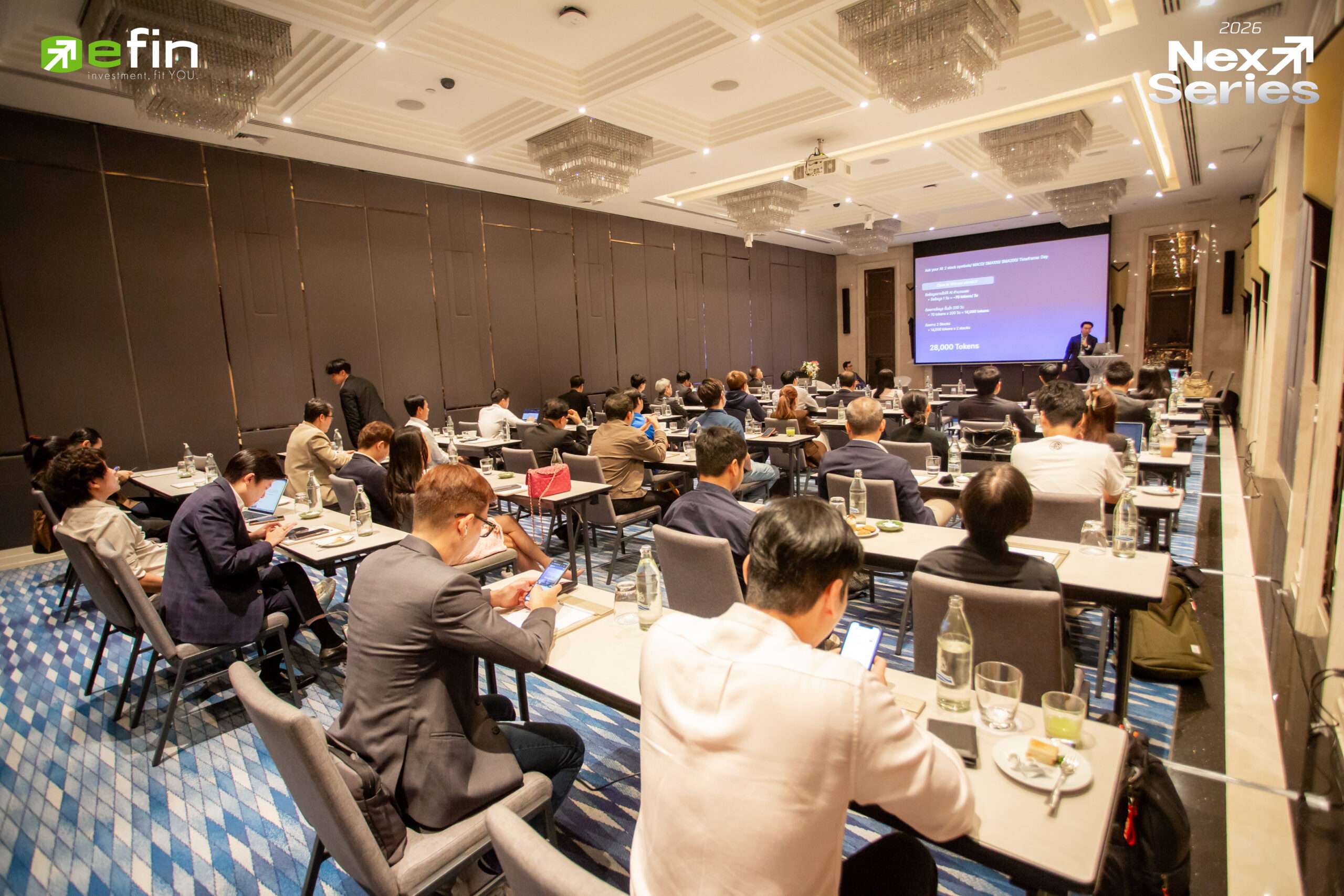 บรรยากาศงานสัมมนา NEXT SERIES 2026 ผู้เข้าร่วมงานกำลังรับฟังการบรรยายเกี่ยวกับแพลตฟอร์มการลงทุนและเทคโนโลยี efinMCP จากวิทยากรบนเวที